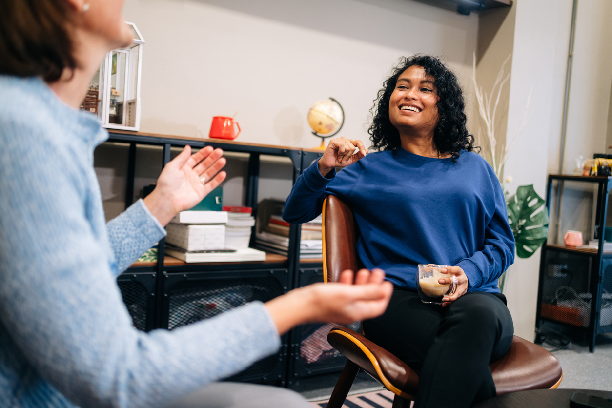 Young Woman Smiling During Informal Office Conversation Two women talking